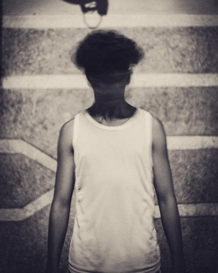 Black and white photo of a man from behind against a stone wall