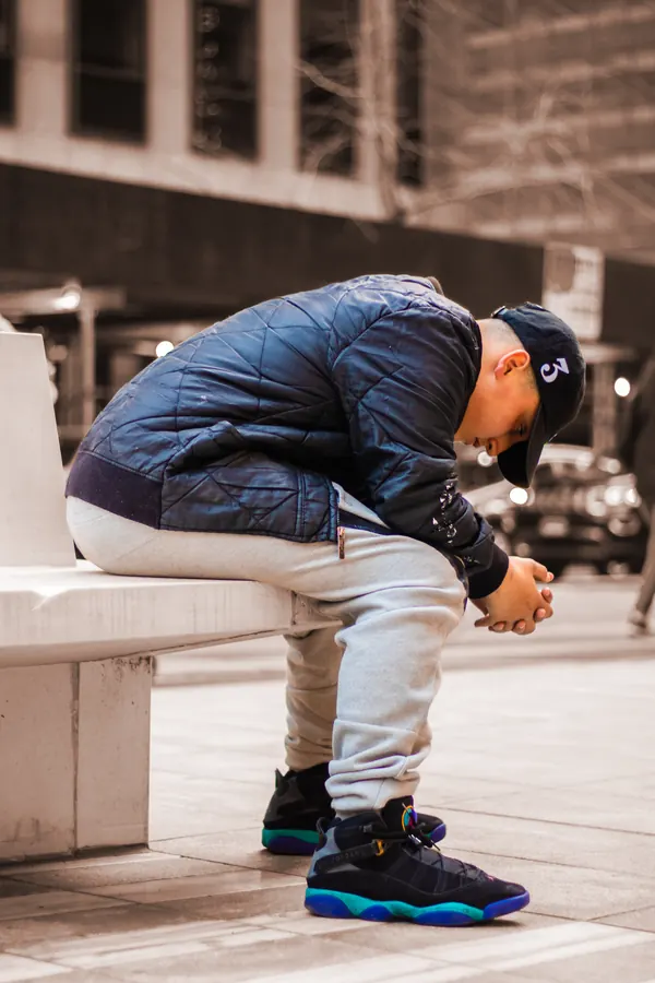Man seated on a bench with his head down