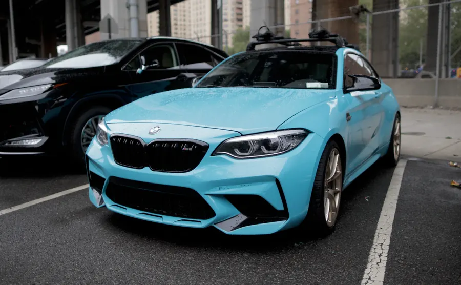Light blue BMW M2 in a parking lot under the FDR