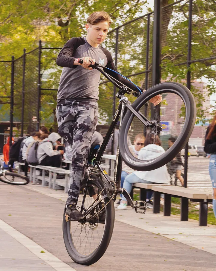 Rider pulling a wheelie on a BMX bike in a park