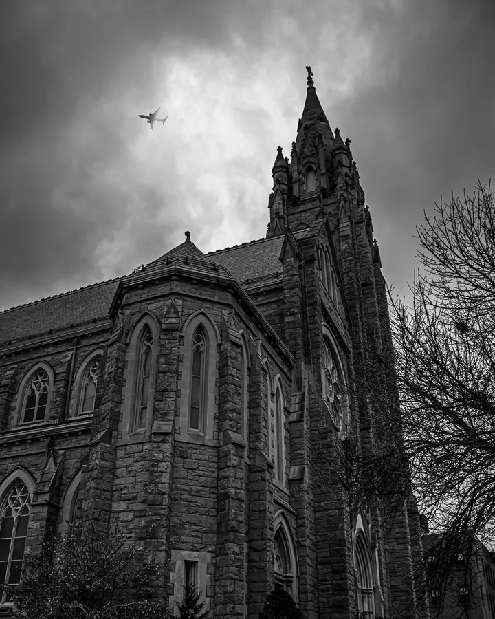 Black and white photo of a stone church under heavy clouds