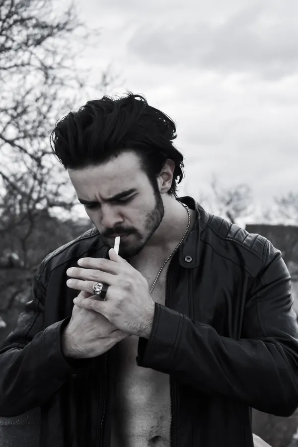 Black and white portrait of a man lighting a cigarette