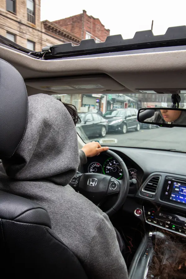 Driver in a grey hoodie seen from the back seat