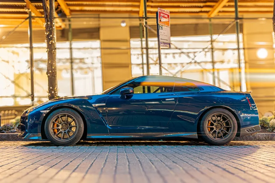 Blue Nissan GT-R in profile in front of a lit storefront