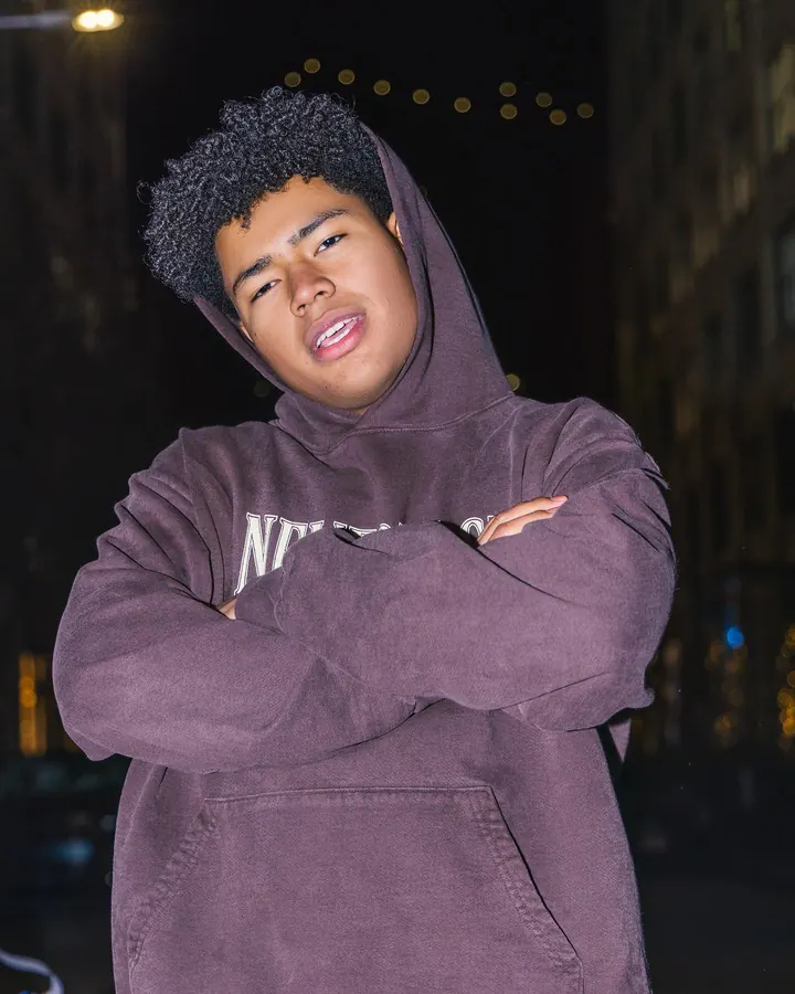 Young man in a hoodie with his arms crossed at night