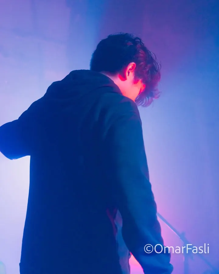 Performer looking down in blue and pink haze