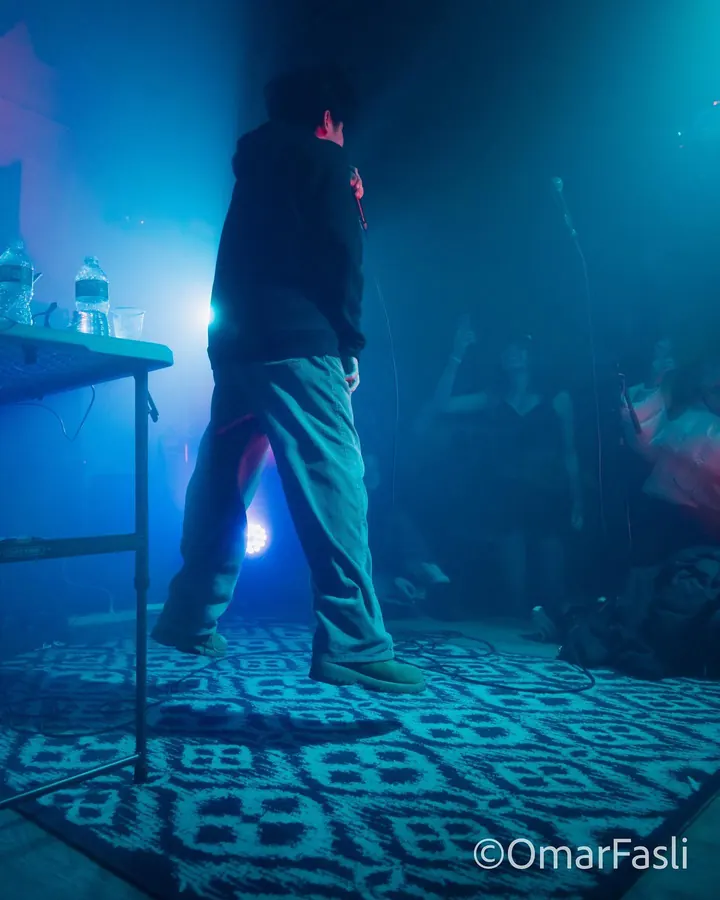 Performer walking a small stage in blue haze