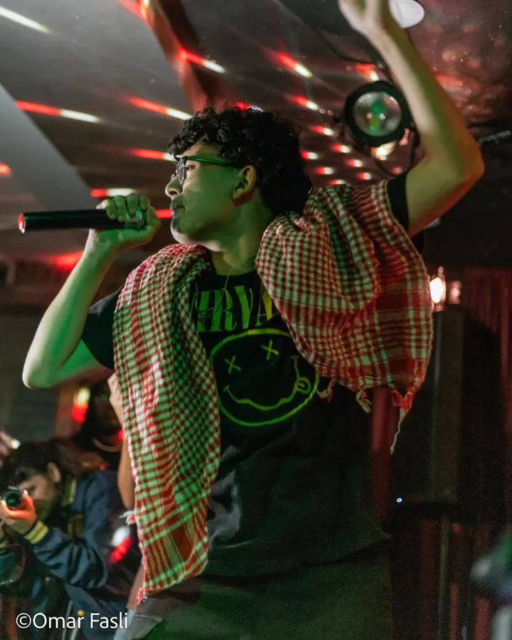 Performer with a raised arm under disco lights