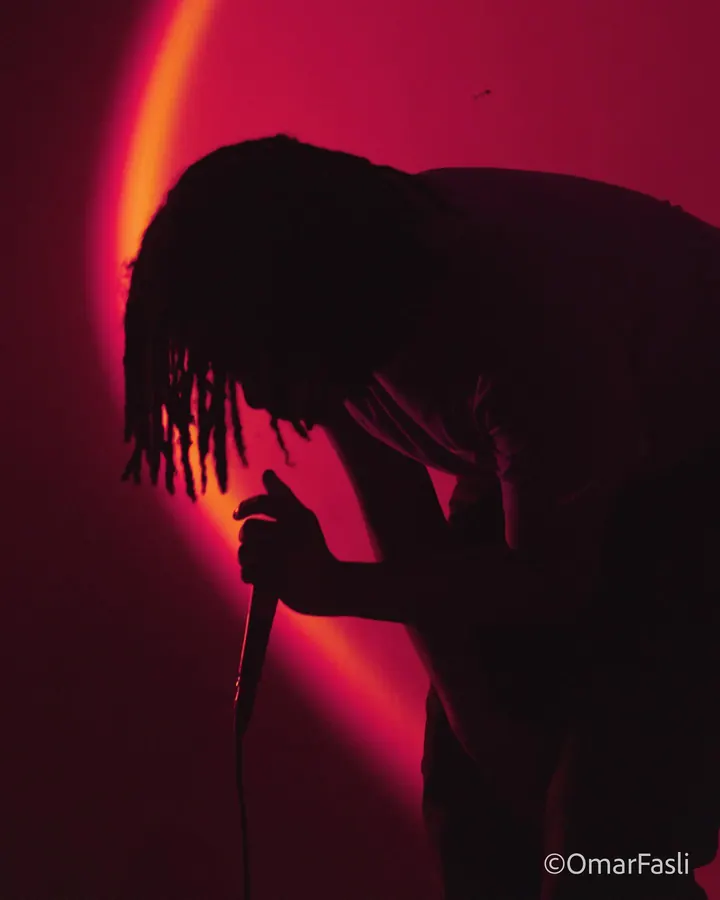 Performer bent over a microphone against a red wall