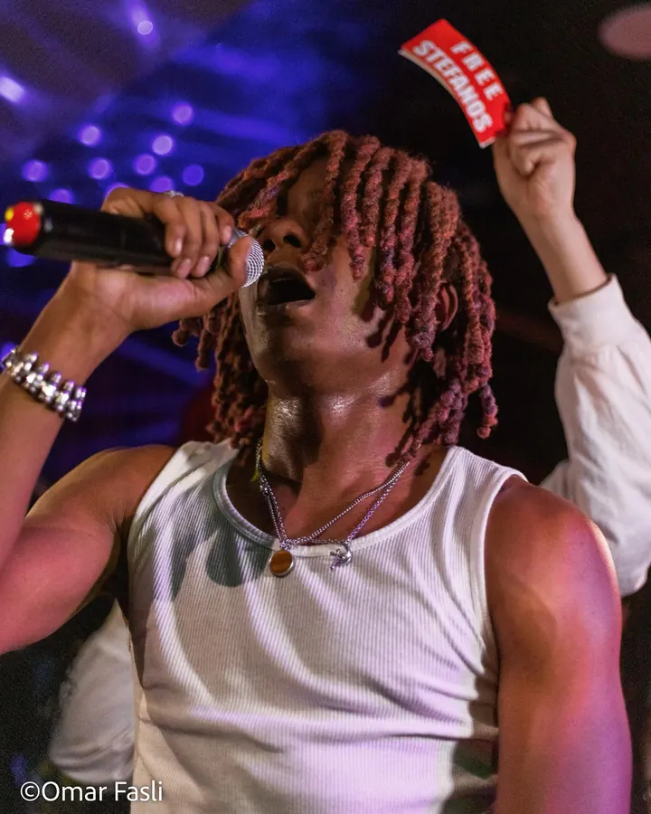 Singer with red locs holding a microphone at a club show