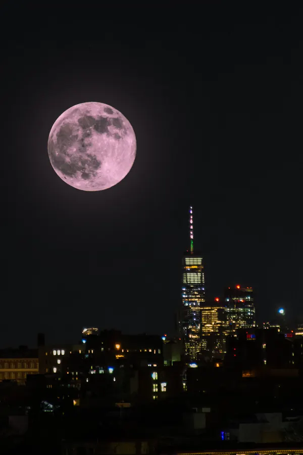 Pink full moon over One World Trade Center at night