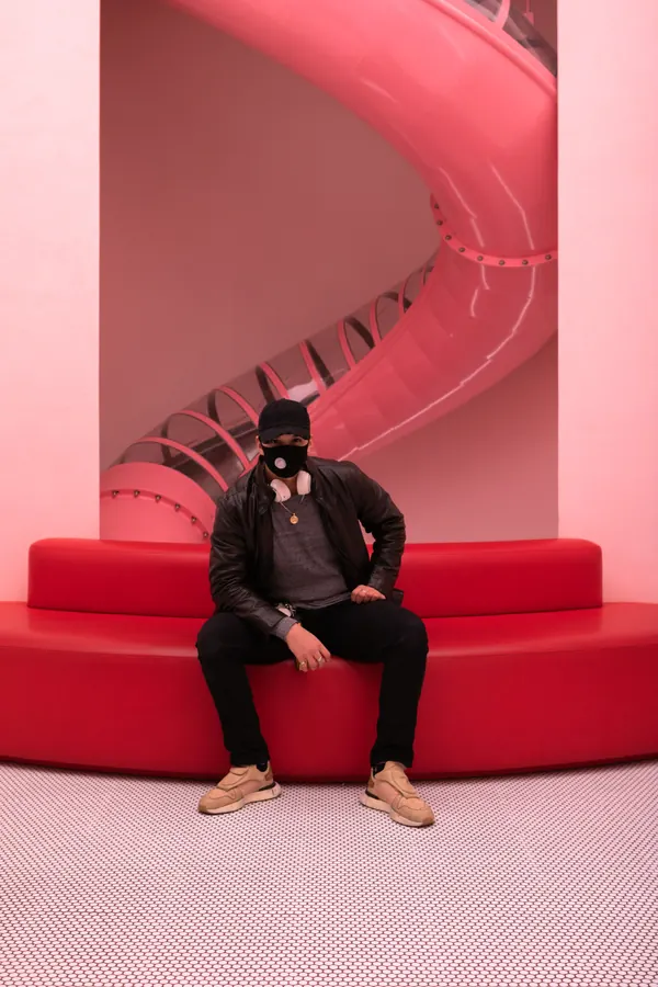 Man seated on a red bench under a pink spiral slide