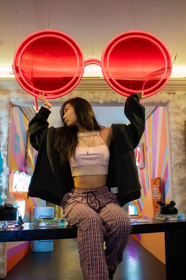 Woman posing under giant red neon glasses
