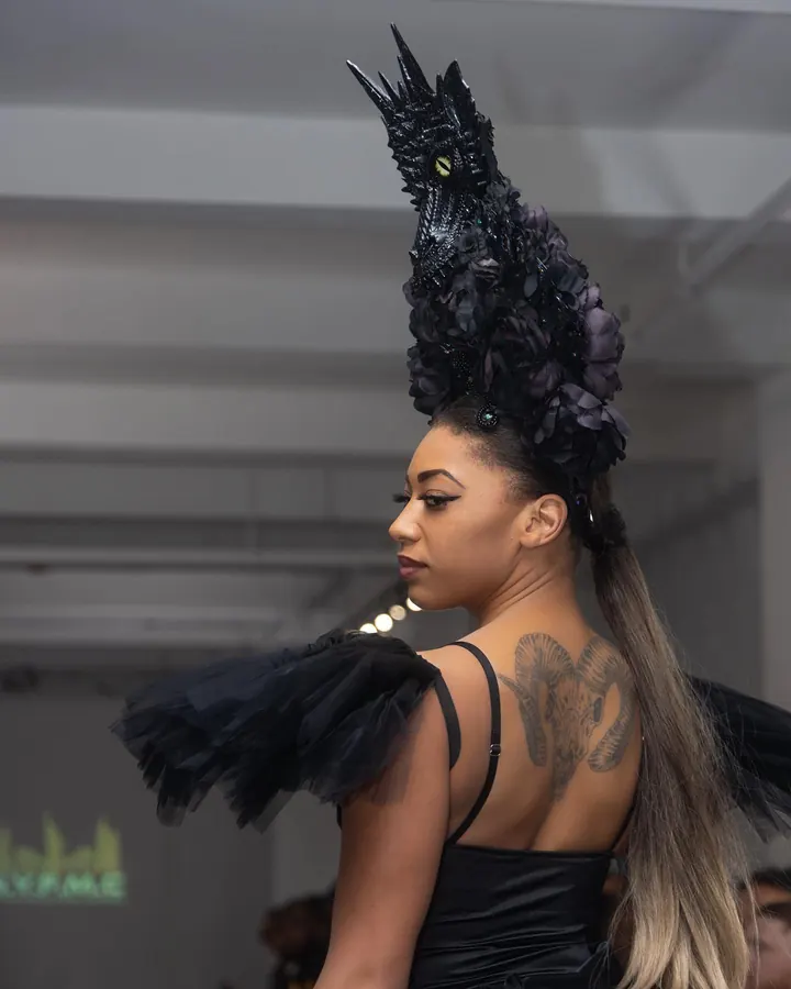 Model in a black feathered headpiece seen from behind on the runway