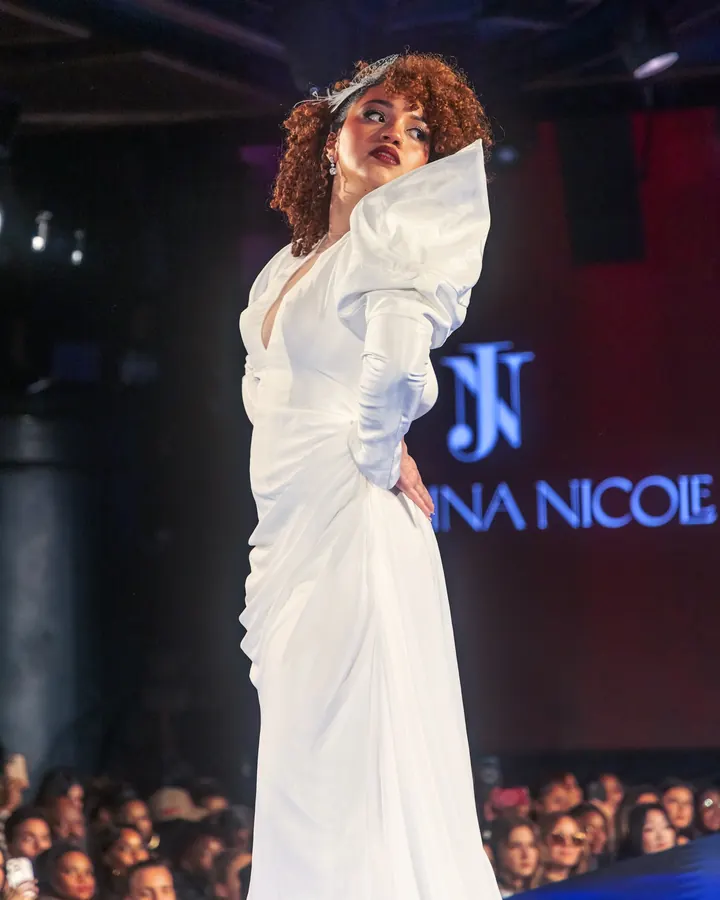 Model in a white gown posing at the end of the runway