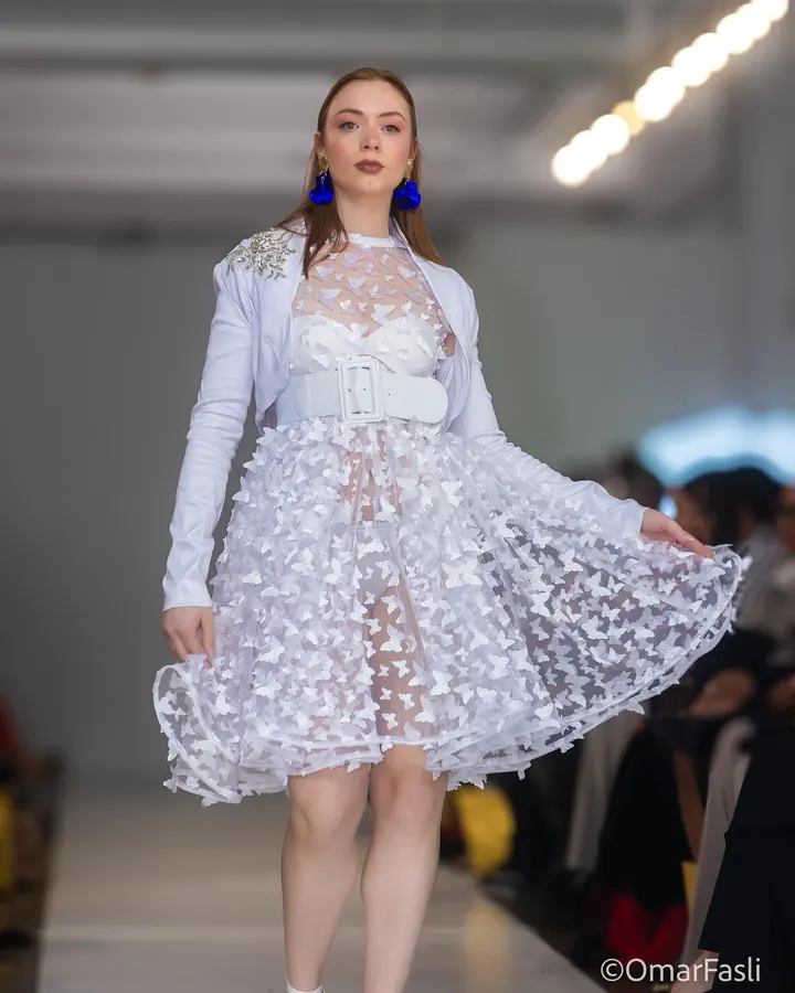 Model twirling a white lace dress on the runway