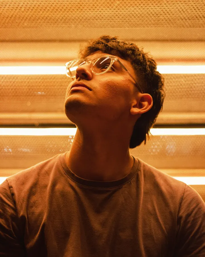 Man in glasses looking up under warm wood slats